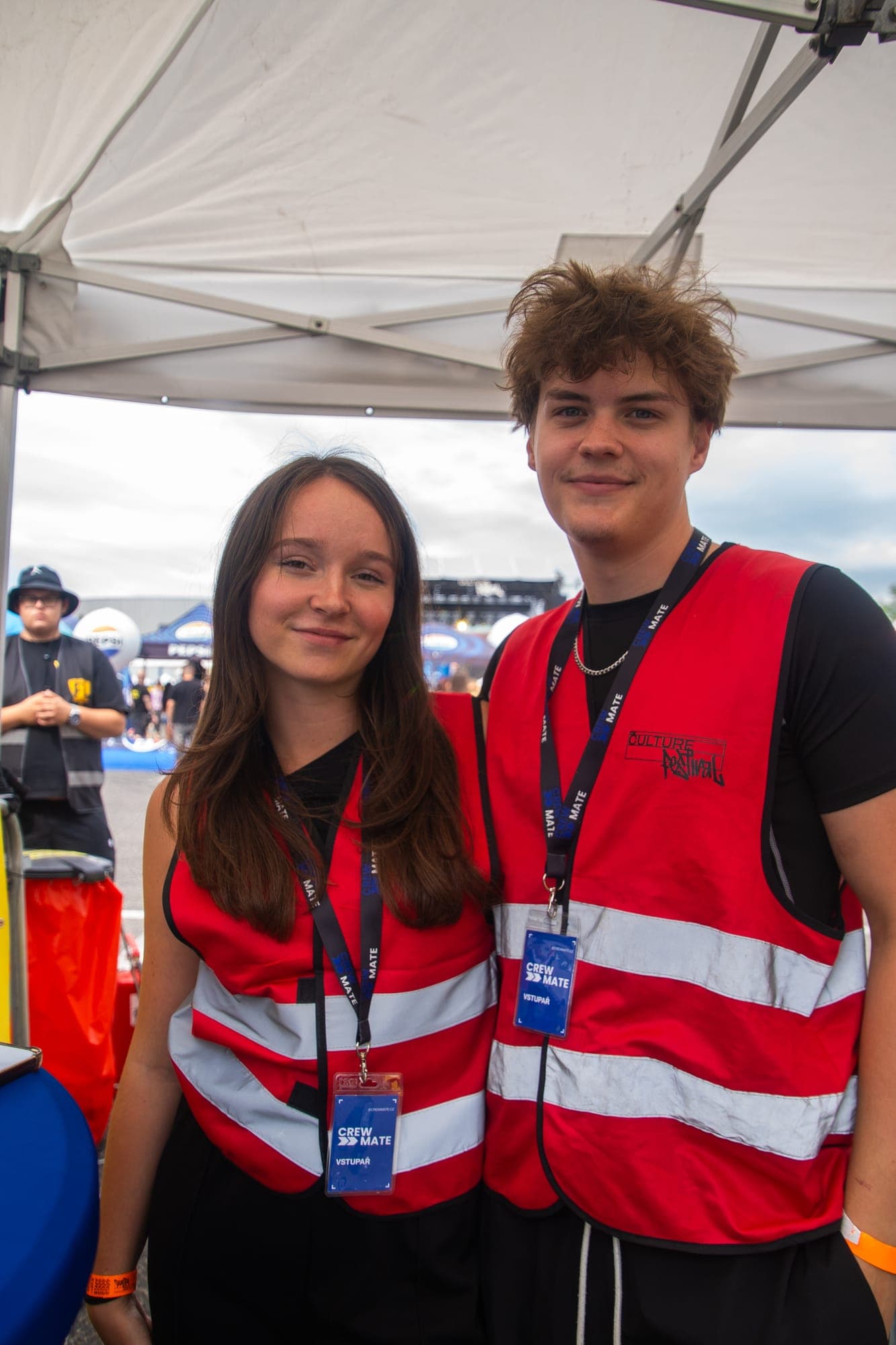 Two Crewmate crew members in high-visibility vests with badges at a festival