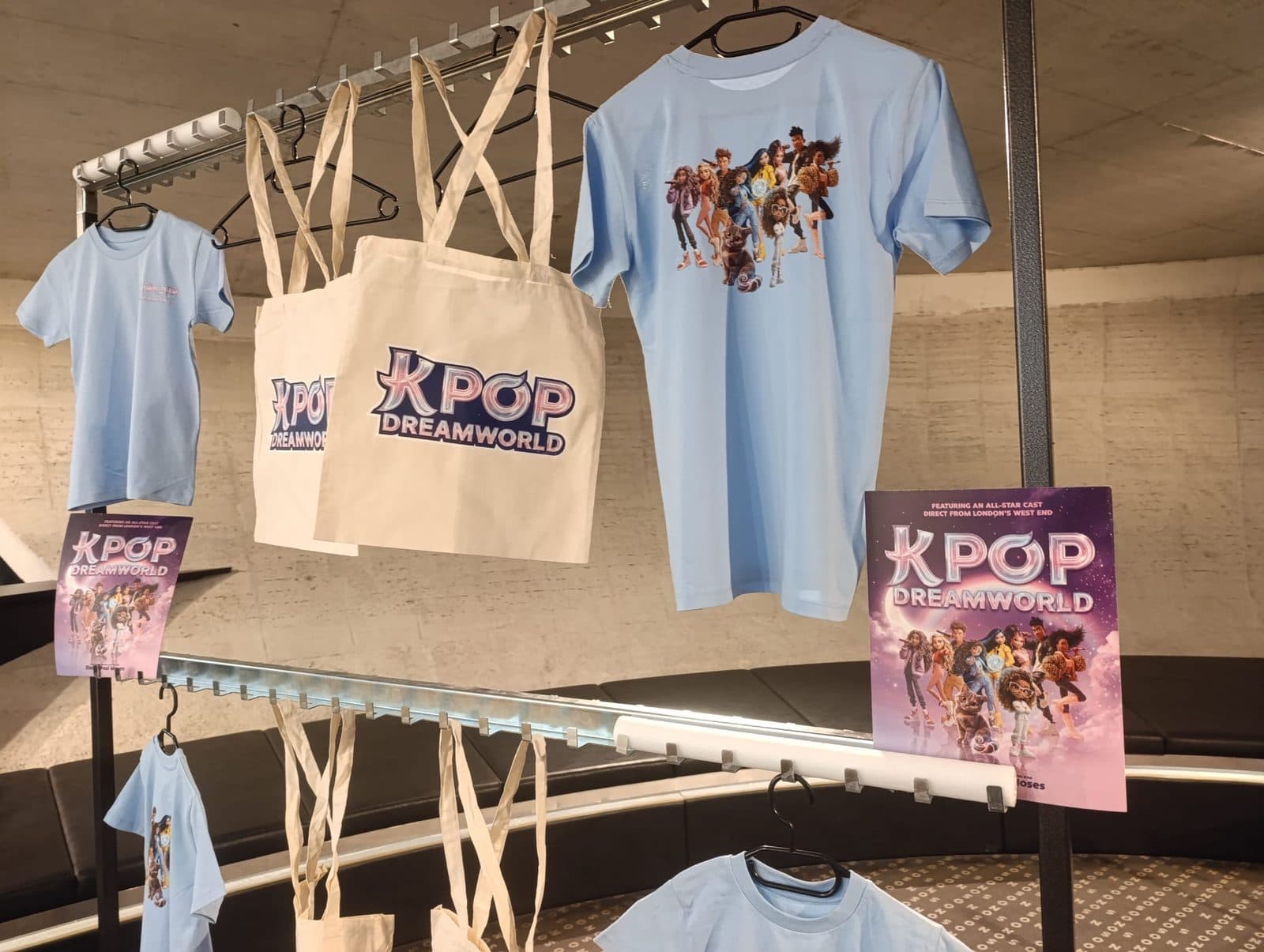 Merch stánek turné K-POP DREAMWORLD: trička, plátěné tašky a plakáty na stojanu