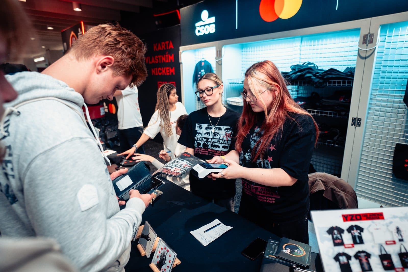 Prodejkyně Crewmate s platebním terminálem u merch stánku labelu Milion+ v O2 areně na koncertu Yzomandiase